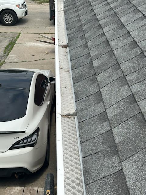 Existing gutter cover on a shingled roof edge before replacement with Gutterglove