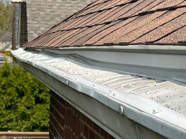 Shingle granules collecting across the surface of an existing gutter cover